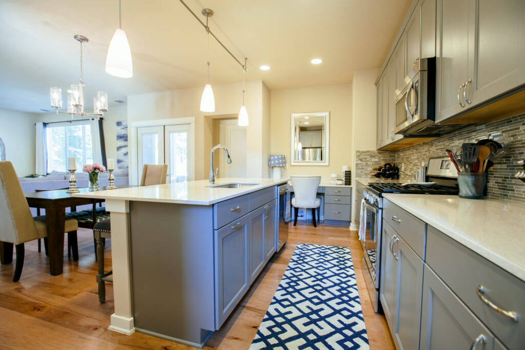 Modern kitchen with gray cabinets, white countertops, stainless steel appliances, a geometric rug, and an adjacent dining area with upholstered chairs—perfect home upgrades to add value in St. Cloud real estate.